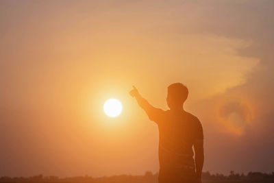 Silhouette man standing against orange sky during sunset