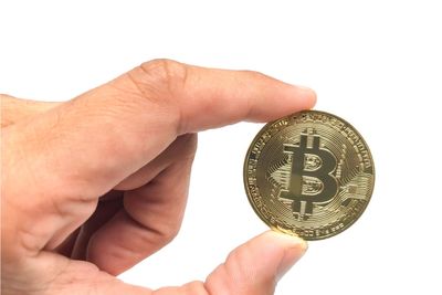 Cropped hand holding bitcoin against white background