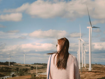 Asian woman with sunglasses see to sky for her boyfriend take photo with wind turbine background