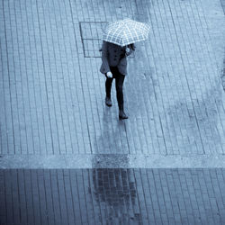 Full length of woman with umbrella walking on wet road