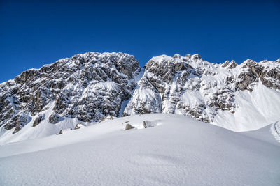 Scenic view of snowcapped mountains against clear blue sky