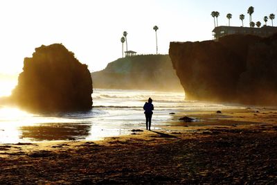 Silhouette woman standing at beach against clear sky