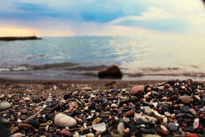 Close-up of pebbles on beach against sky during sunset