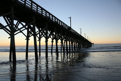 Silhouette pier over sea against sky during sunset