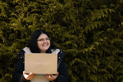 Portrait of a smiling young woman standing against trees