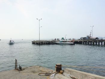 Boats moored at harbor against clear sky