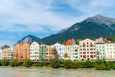 Residential buildings by mountains against sky