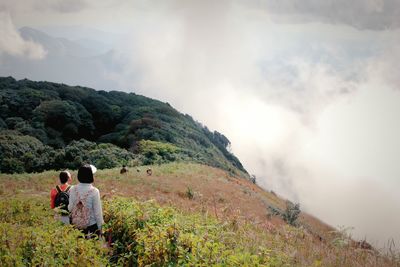 Rear view of man and woman hiking on mountain in foggy weather