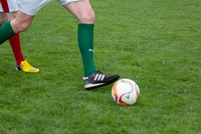 Low section of person playing soccer ball on grass