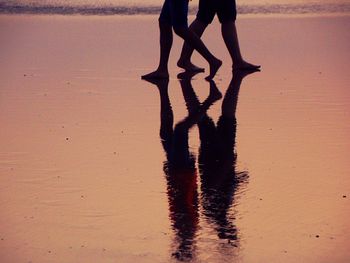 Low section of silhouette people standing on beach
