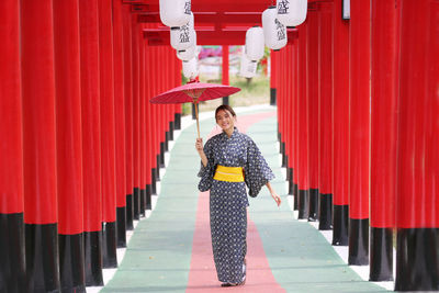 Woman standing by red umbrella