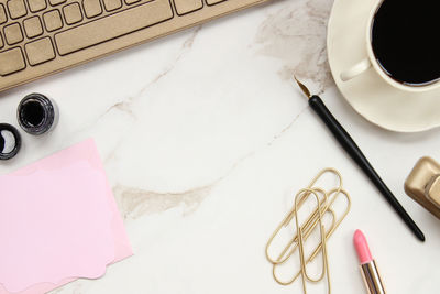 Directly above shot of coffee cup with office supply and computer keyboard on table