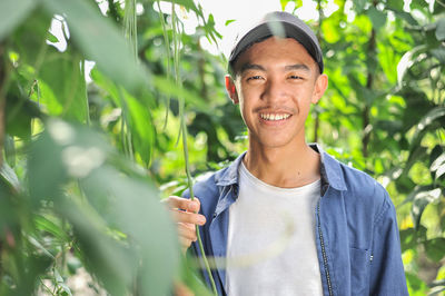 Happy of young asian farmer male holding the long beans