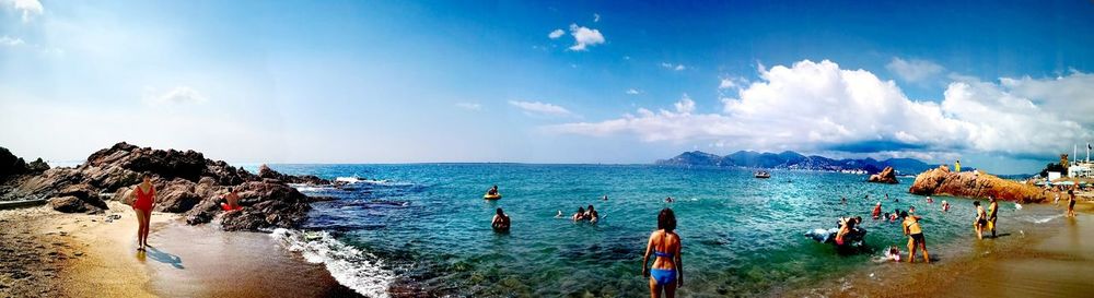 Panoramic view of people on beach against sky