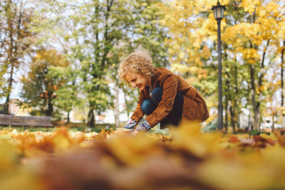 Young woman playing with autumn leaves at park