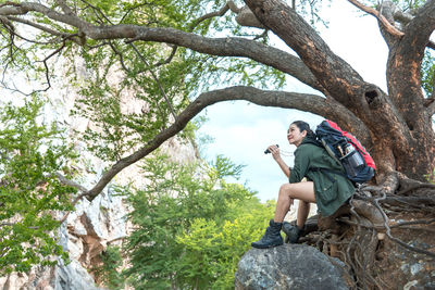 Young man sitting on tree trunk