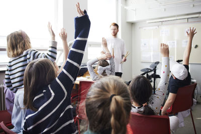 Children raising hands in class