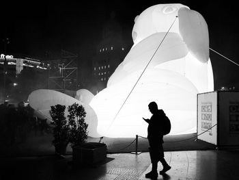 Rear view of man walking on illuminated street at night
