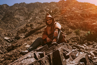 Portrait of young man sitting on rock