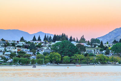 Town by sea against sky during sunset