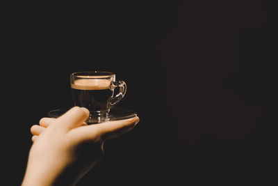 Midsection of person holding drink against black background