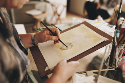 Senior artist painting with paintbrush at home