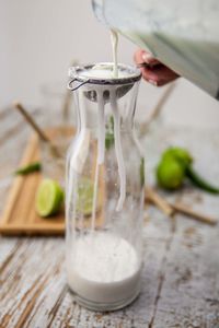 Cropped image of hand pouring drink into glass jar