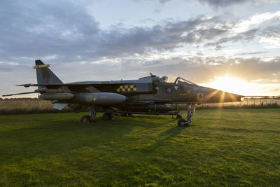 Airplane on field against sky during sunset