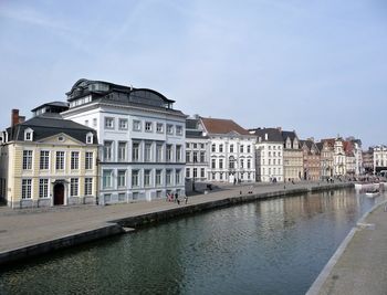 Buildings by river against sky