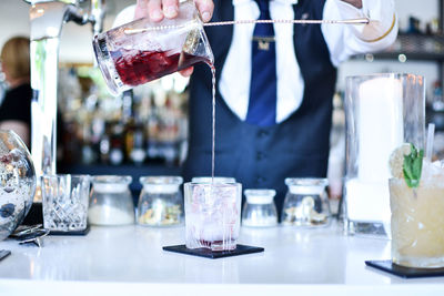 Midsection of bartender preparing drink