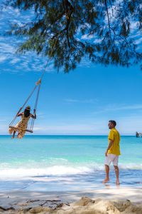 Rear view of woman standing on beach against sky