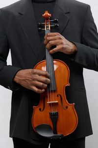 Midsection of businessman playing violin against white background