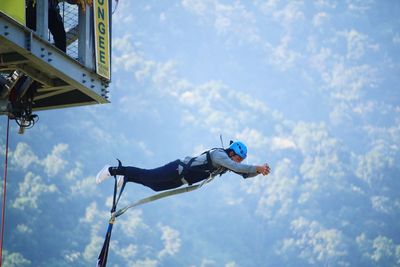 Low angle view of man paragliding against sky