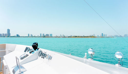 People on sea by buildings against clear blue sky