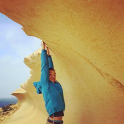 Portrait of young man hanging on rock formation