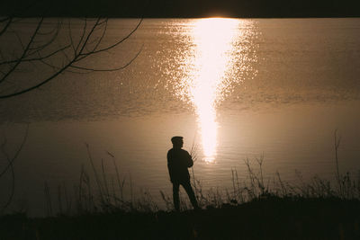 Silhouette man standing on beach against sky during sunset