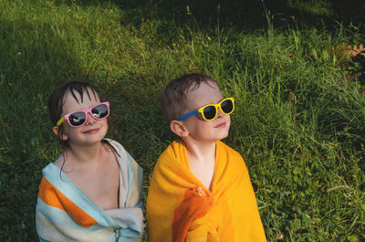 Wet cheerful children in sunglasses in a towel. boy and girl look away. 