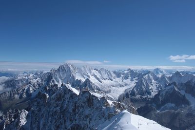 Scenic view of snowcapped mountains against blue sky