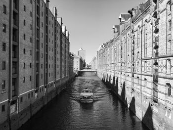 Canal amidst buildings against clear sky in city