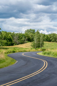 Road by trees against sky