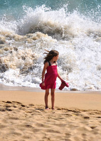 Full length of girl at while water splashing at beach