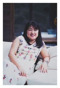 Portrait of a smiling young woman sitting outdoors