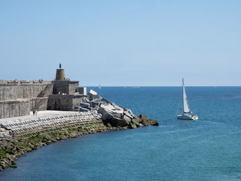 Sailboats in sea against clear blue sky