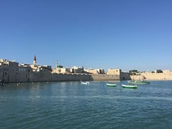 Boats moored at harbor against clear sky