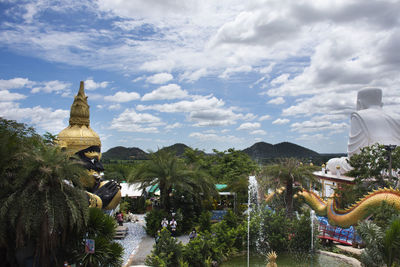 Statue amidst trees and buildings against sky