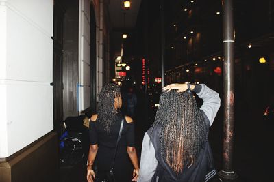 Women walking on sidewalk of city street at night