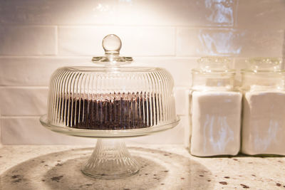 Cake in stand on table against wall