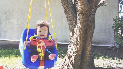 Portrait of happy boy playing on tree trunk