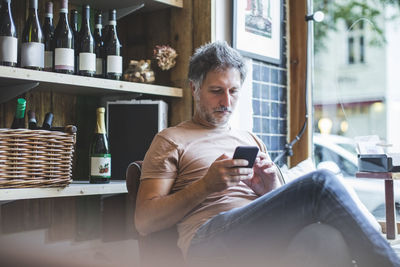 Man using smart phone while sitting in laptop