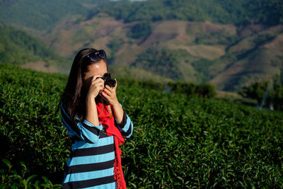 Woman photographing with camera on field